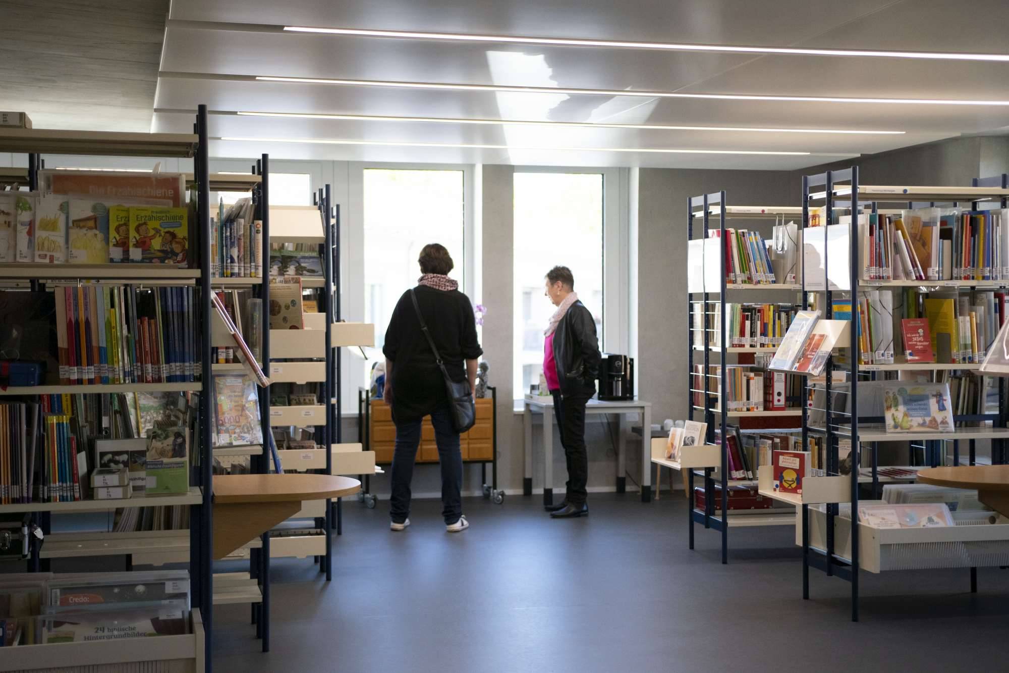 Quelle: ©EvKirchePF Bücherregale im Vordergrund im Hintergrund zwei Frauen
