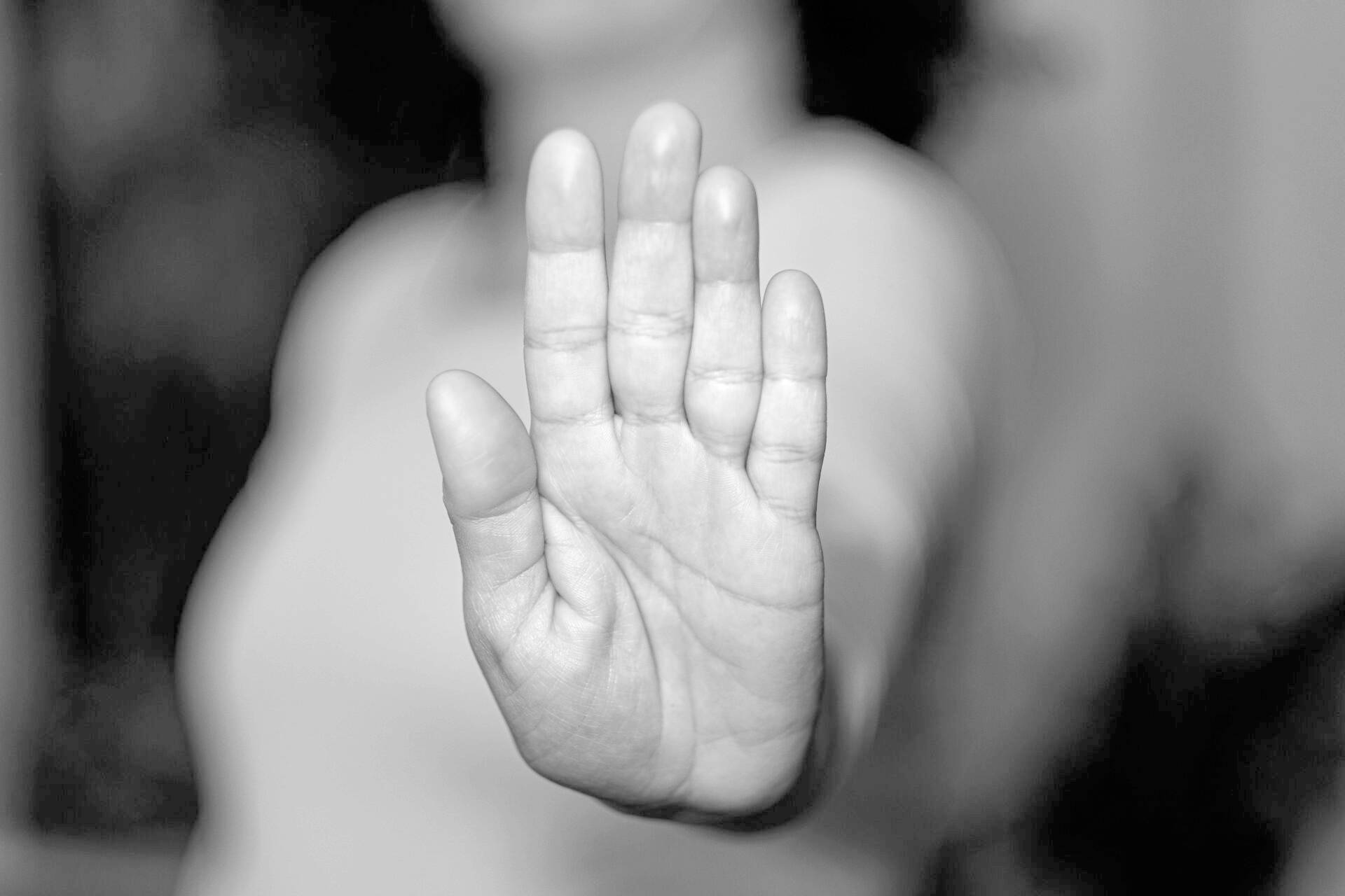 Eine Frau streckt ihre Handfläche aus und in die Kamera. Der Fokus liegt auf der Handfläche, der Rest ist verschwommen. Das Bild ist schwarz-weiß.
